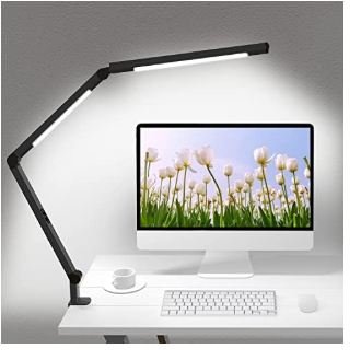 Black adjustable LED desk lamp with multi-joint swing arm positioned over modern white desk workspace with iMac computer, keyboard, mouse and coffee cup