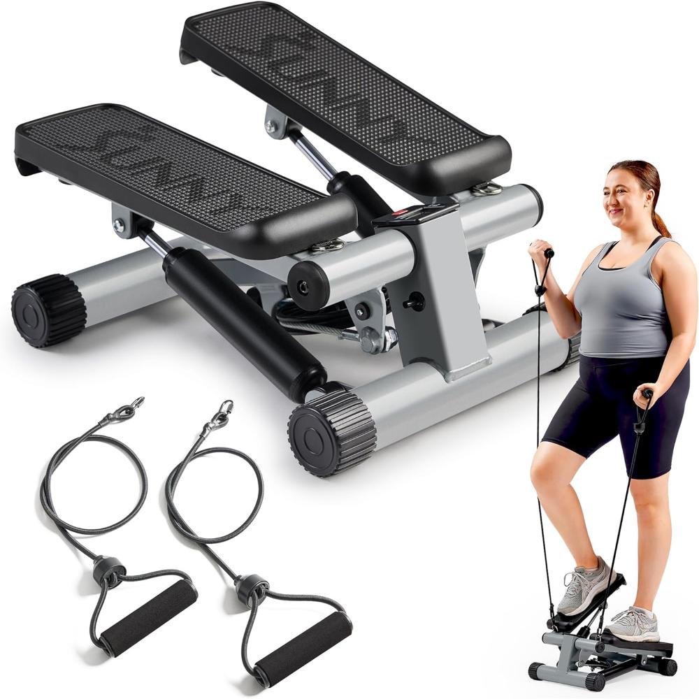 Silver and black compact mini stepper machine with textured foot pedals, resistance bands with handles, and woman using it in home setting