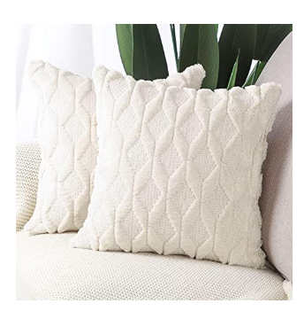 Cream colored cable knit throw pillow covers with textured pattern on neutral sofa with tropical plant decor in background