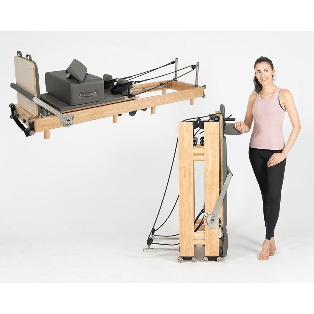 Wooden Pilates reformer with padded carriage, adjustable pulley system, resistance springs, headrest, foot bar, and woman demonstrating use in fitness studio
