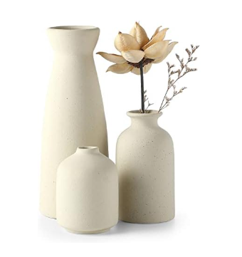 Three cream-colored ceramic vases in varying shapes and sizes, arranged together with a dried flower stem in the tallest one.