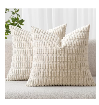 Two cream-colored textured throw pillows with a tufted geometric pattern sitting on a light sofa.